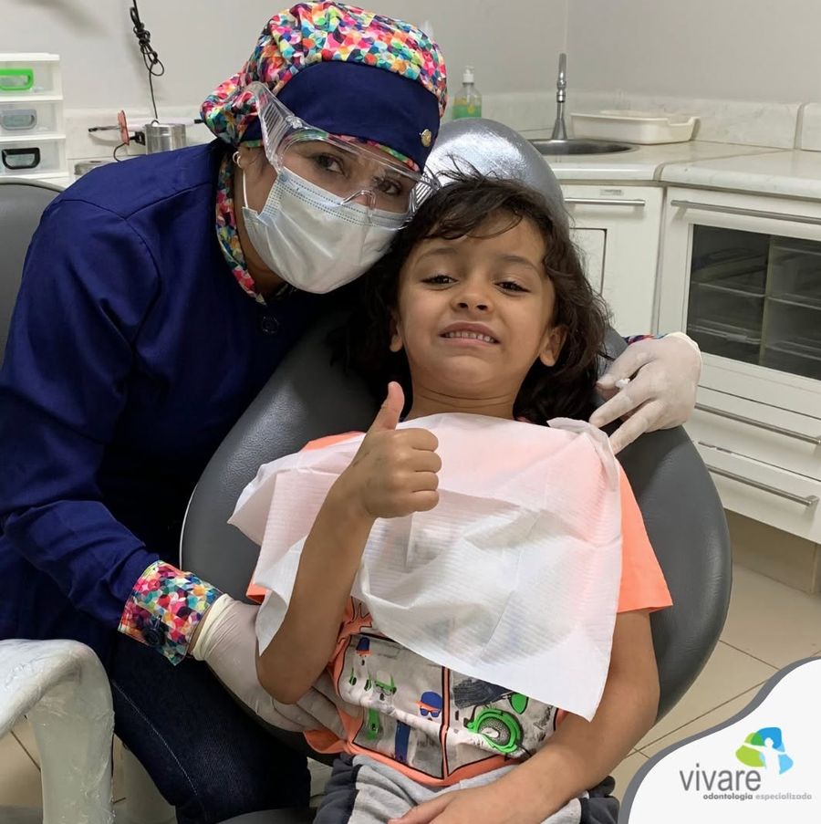 Paciente criança fazendo joinha ao lado da dentista